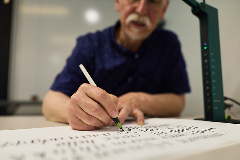 Man writing calligraphy at Reed Reunions.